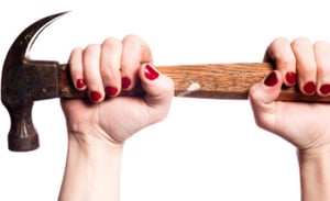 A hand with red fingernails holding a hammer