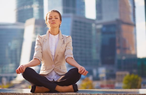 women meditating in front of city backdrop